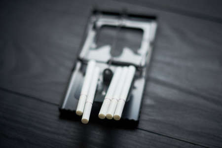 The meanness of cigarettes, the harm of smoking, habits concept. Cigarettes in a mousetrap on a black background.の写真素材