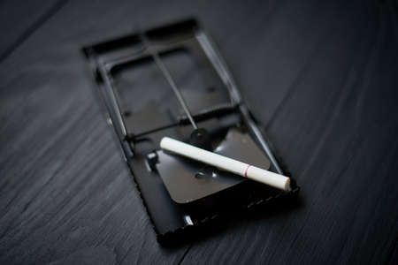 Cigarette in a mousetrap on a black background.の写真素材