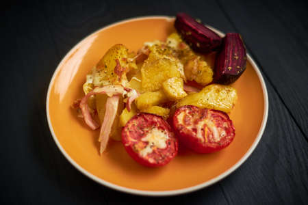 Baked potatoes with bacon, cheese and tomatoes in a plate.の写真素材
