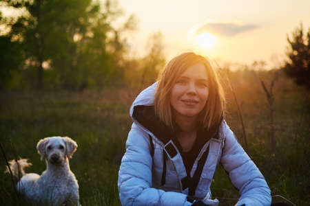 Woman with a dog in the park at sunset.の写真素材