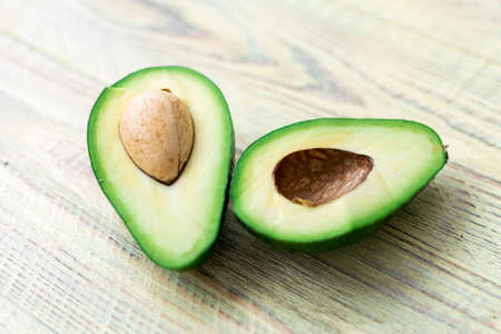 Avocado cut in half on a wooden background.