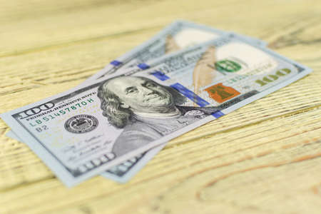 Hundred dollar bills on a wooden background.の写真素材