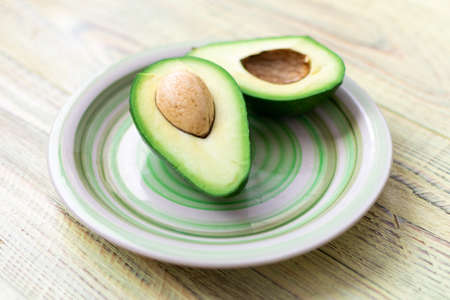 Avocado cut in half on a wooden background.