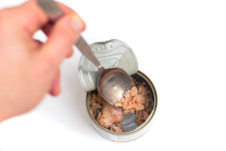 Tuna in an open tin can on a white background. Eat fish from a can.