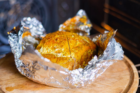 Baked piece of meat with spices in foil in the oven.
