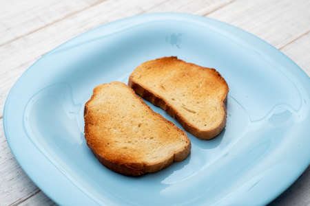 Toasted white bread on a blue plate on a white wooden background. Minimalism.の写真素材
