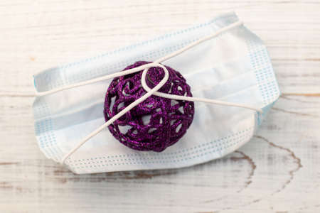 Christmas tree toy ball and medical mask. New year holidays and coronavirus concept.