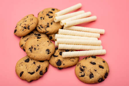 Cookies with chocolate and sweet rolls on a pink background. Sweet background.