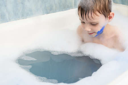 The baby in the bubble bath is smeared with blue paint. Children's games, entertainment.の写真素材