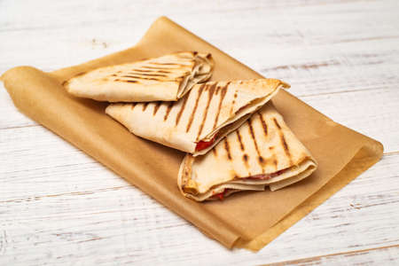 Pita, tortilla with cheese and ham on a white wooden background. A light, healthy snack.