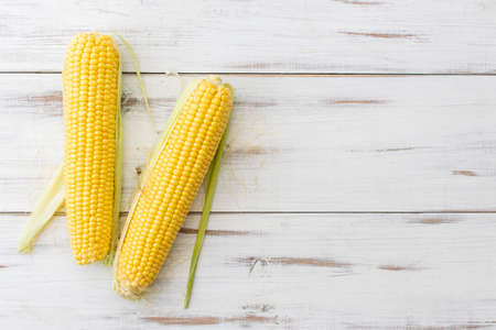 Whole corn on a white wooden background. Vegetarian food.の写真素材