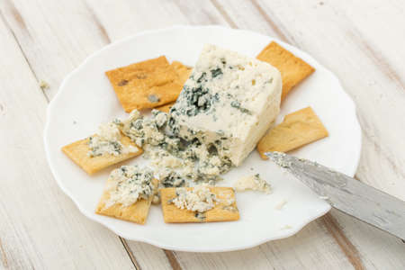 Blue cheese and cracker on a white plate on a wooden background.の写真素材
