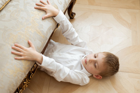 A young boy is hiding under the sofaの写真素材