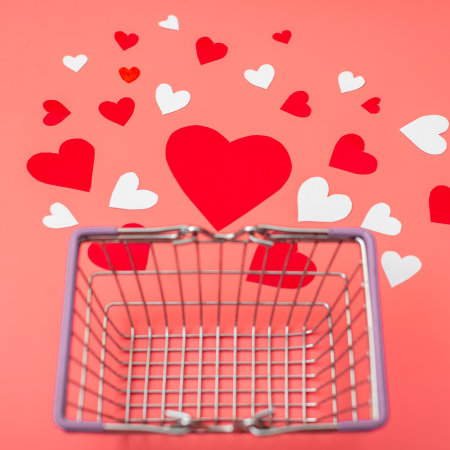 Shopping for valentine's day concept. Shopping basket and hearts on a red background.