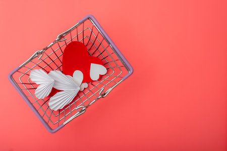 Shopping for valentine's day concept. Shopping basket and hearts on a red background. Place for your text.の写真素材
