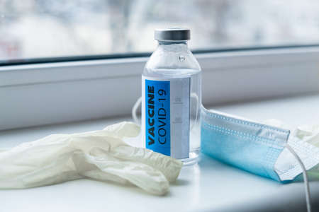 vaccine, medical mask and gloves near the window.