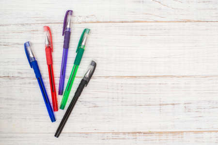 Multi-colored pens on a white wooden background.の写真素材
