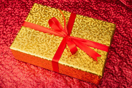 Gift in a gold package on a red background.の写真素材