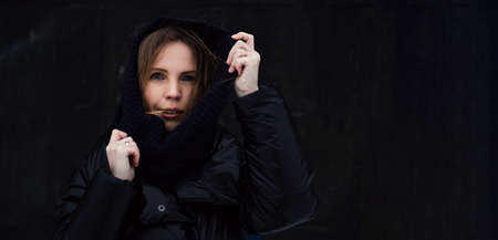 Middle-aged woman in warm, winter clothes on the street on a black background. Place for your text.