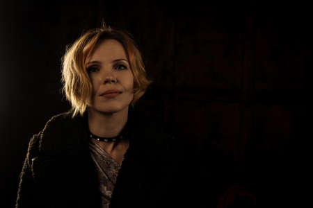 Middle-aged woman in dress and coat on a black background. Place for your text.