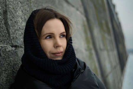 Midlife crisis woman. A woman stands thoughtfully leaning her elbows against a concrete wall in warm...