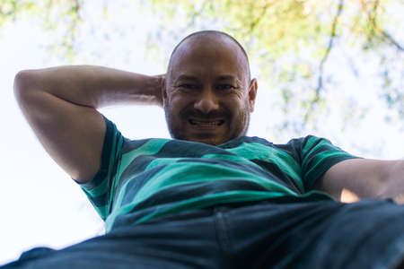 Contented plump unshaven middle-aged man smiling outdoors.の写真素材