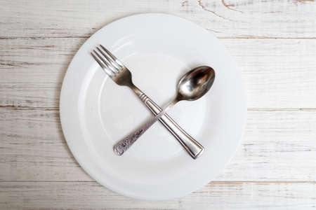 The spoon and fork are on an empty plate. Diet concept, intermittent fasting.の写真素材