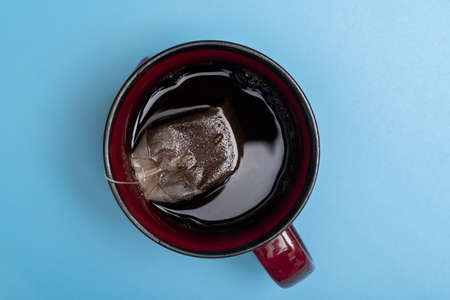 Tea bag in a cup on a blue background.