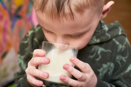 The boy is drinking milk from a glass.の写真素材