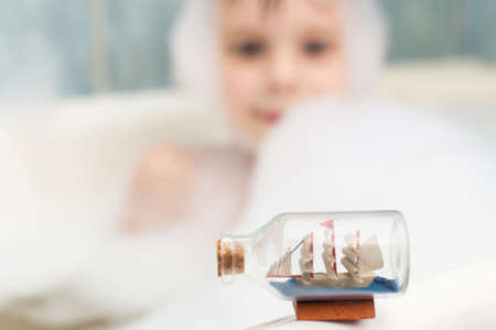 The boy pulls his hand to the boat in the soapy bath. Hygiene, cleanliness concept. Children's games...