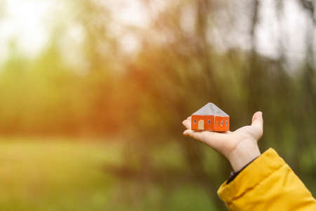 A toy house in the hands of a child. The concept of buying, renting, mortgage housing.の写真素材