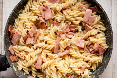 Pasta with bacon, sausage in a pan with a creamy sauce.の写真素材