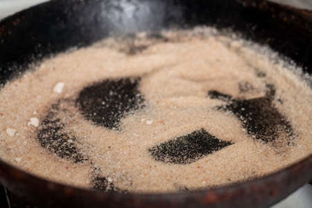 Ignite a cast iron skillet with salt on the stove. Preparing the pan for use.の写真素材