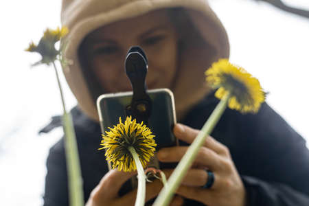 Phone lenses for macro photography. A woman holds a mobile phone with a macro attachment in her...