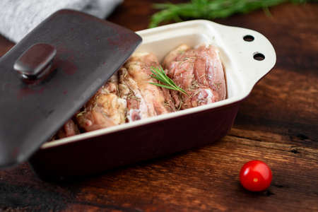 Raw chicken thighs in a baking dish on a wooden background. Preparation for baking.の写真素材