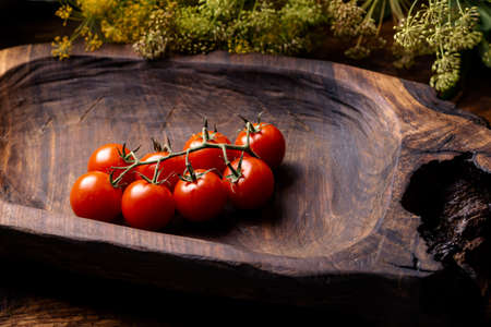Cherry tomatoes with herbs on a wooden background.の写真素材