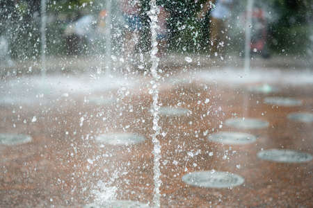 Fountain water jets rising from marble tiles.の写真素材