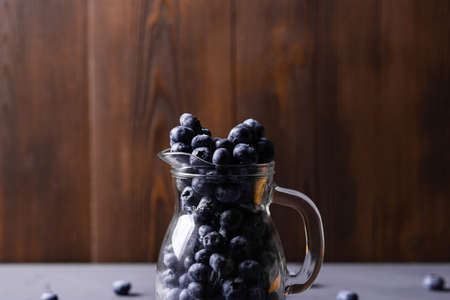 Blueberries in a glass jug on a gray concrete background. The benefits of berries, vegetarianism concept.の写真素材
