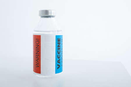 Harm, danger of vaccine and vaccination against coronavirus concept. A container with a vaccine and warning labels.の写真素材