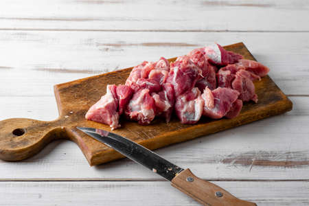 Sliced pieces of raw meat on a cutting board. Pork or beef is prepared for cooking.