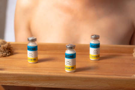 Harm, death from coronavirus vaccine, side effects concept. An unrecognizable woman holds on a tray a container with a vaccine with the emblem of a sign of danger.の写真素材