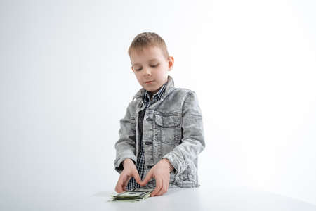 Child and money. Young boy holding dollars in his hands on a white background. Personal money concept.の写真素材