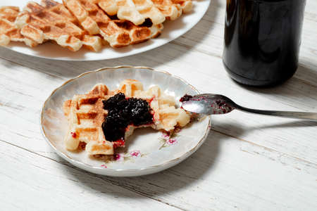 Belgian waffles with berry jam on a white wooden background.の写真素材