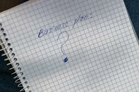 Business plan and question mark written on a notebook. Reflections on enrichment, entrepreneurship.の写真素材