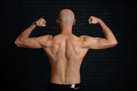 A naked torso with hair of an ordinary man in good physical shape in jeans on a dark background.の写真素材