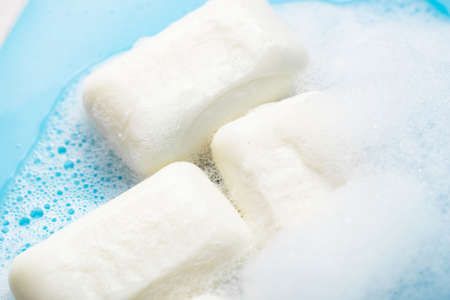 Global Handwashing Day. Hygiene concept, background. Pieces of soap in foam close-up on a light blue background.の写真素材