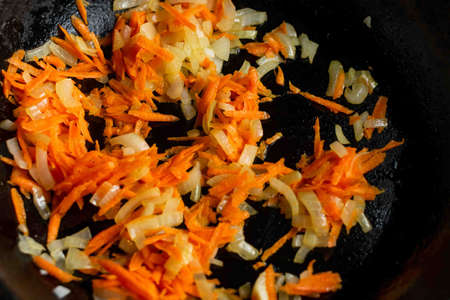 Fried onions with carrots in a pan close-up. Preparation of ingredients for cooking.の写真素材