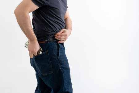 An unrecognizable man puts dollars in his jeans pocket. Isolated on a white background.の写真素材
