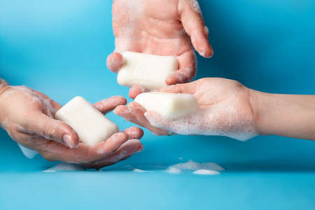 Global Handwashing Day, personal hygiene concept. Three hands in soapy foam with soap on a blue background on a light blue background.の写真素材