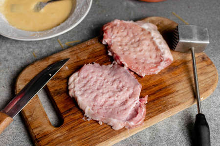 Two pieces of beaten meat on a cutting board. Cooking pork chops.の写真素材